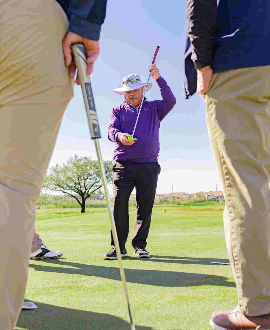 John Hughes giving putting guidance to clients on the green at ChampionsGate